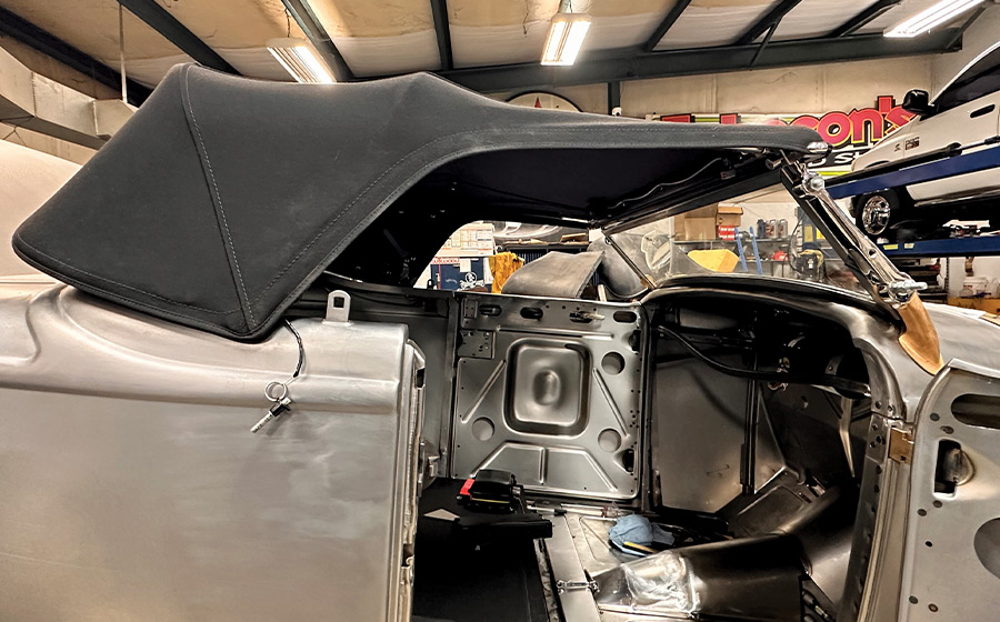 Custom black roadster with cloth top on raw steel body, showcasing finished stitching and fitment