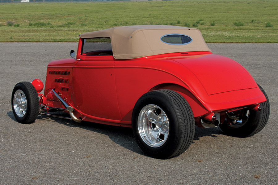 Rear view of 1933 Ford Roadster with chopped tan top, oval rear window, and smooth tail panel