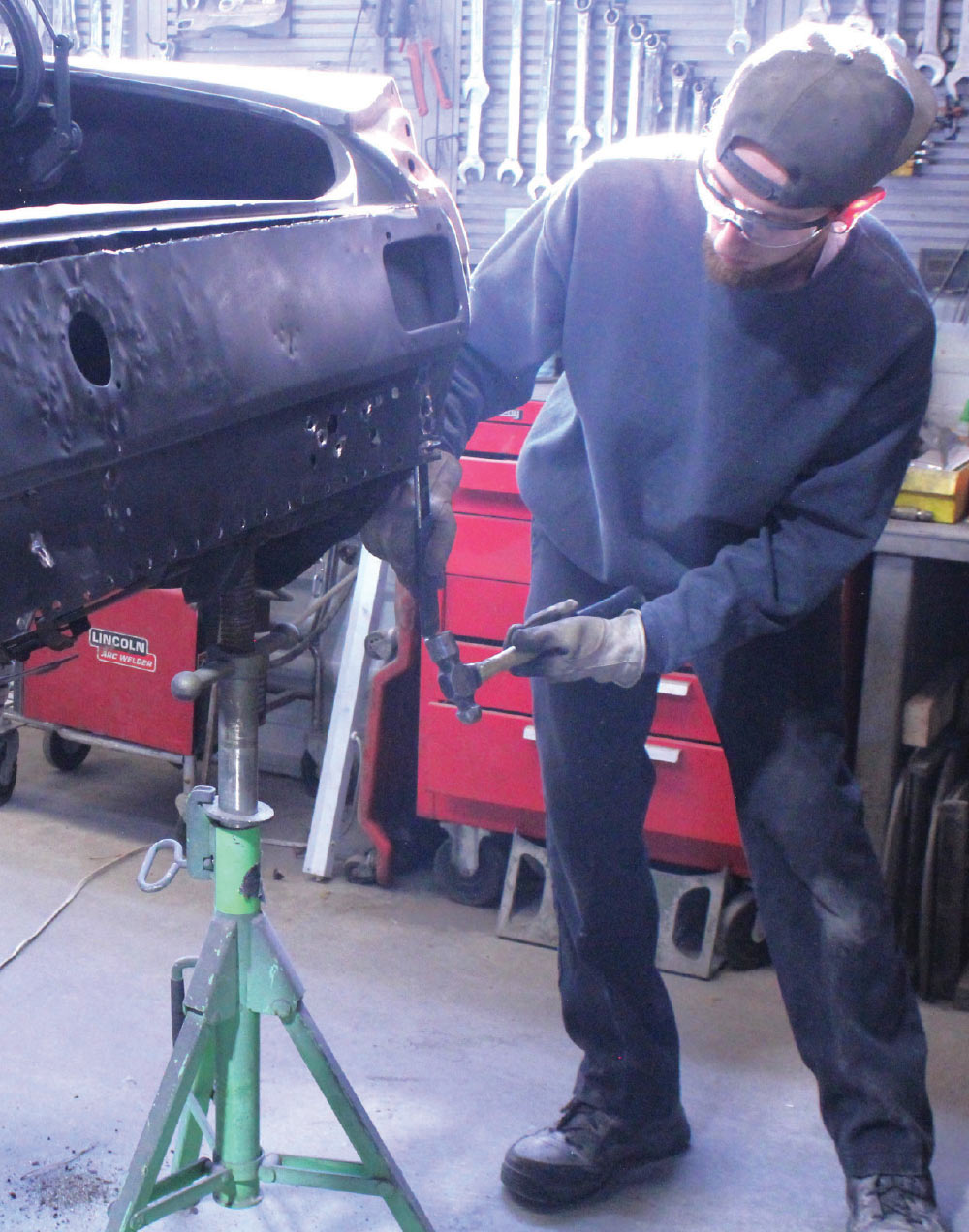 removing damaged 1965 mustang tail panel with hammer and chisel