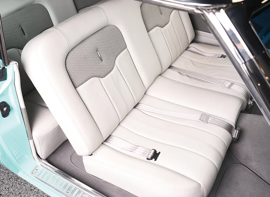 1963 Ford Falcon rear seats in white leather with textured inserts and lap belts.