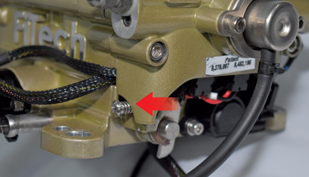 Close-up of FiTech throttle linkage and wiring harness on gold anodized EFI unit