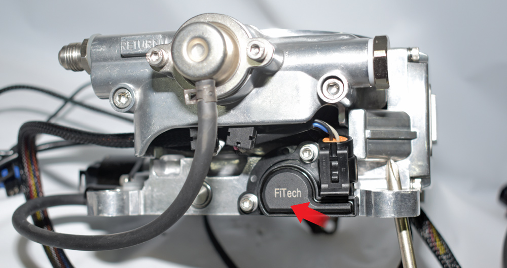 FiTech throttle body side showing TPS sensor and labeled return fuel port