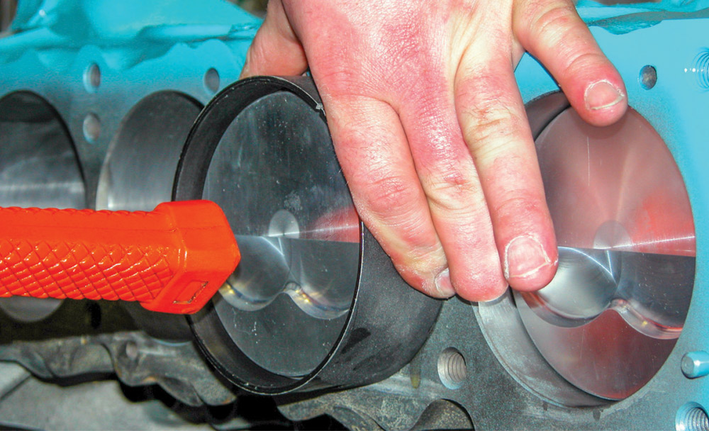 Forged piston with valve reliefs installed into Pontiac 428 block using ring compressor