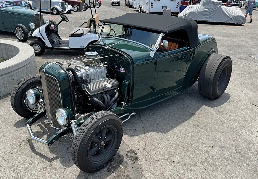 1932 Ford highboy roadster in dark green with blower, steel wheels, and black top