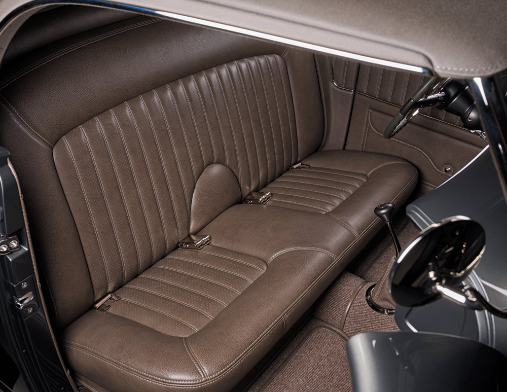 1936 Ford highboy brown leather bench seat with custom stitching, seatbelts, and shifter visible in cabin