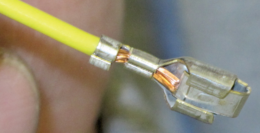 close-up crimped terminal on yellow wire showing clean copper connection