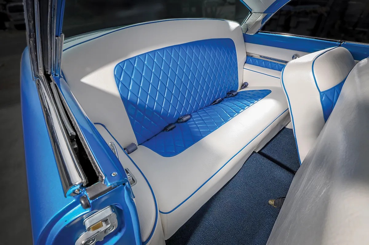 Custom rear bench seat of a classic car featuring two-tone white and bright blue diamond-quilted leather upholstery and matching piping