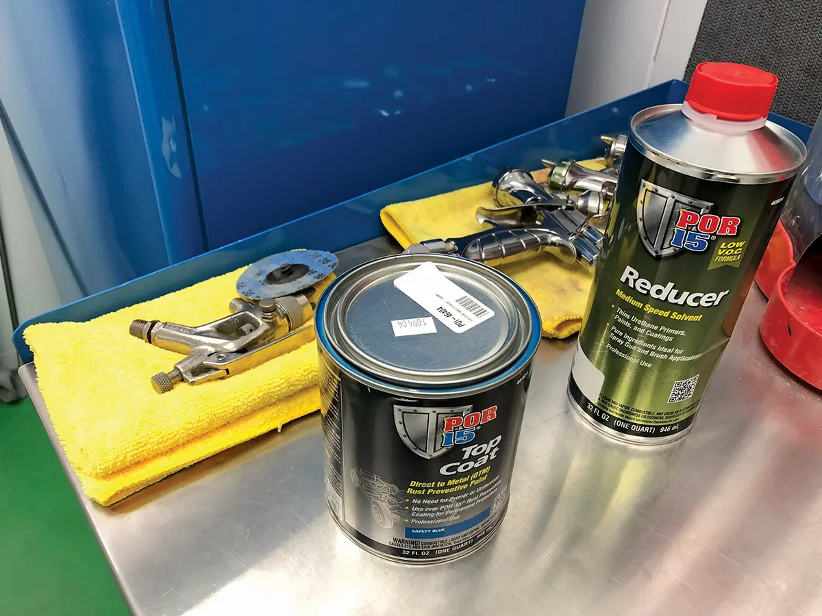POR-15 top coat and reducer with spray gun on clean workstation