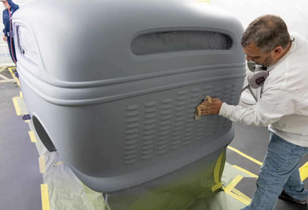 Technician prepping 1930s Ford coupe body for metallic paint application