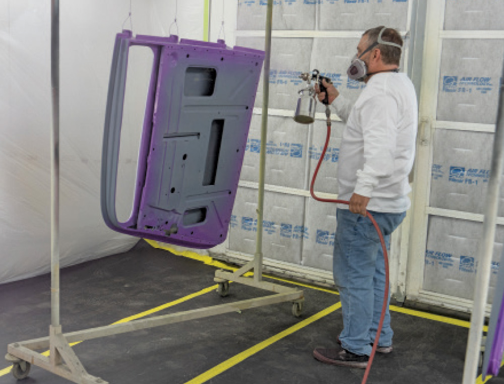 Spray painting interior of 1930s Ford coupe door with metallic purple finish