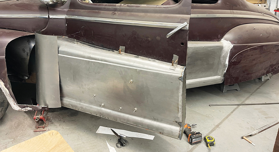 1947 Ford coupe door open, fadeaway fender panels attached, tape measure, drill, and scissors visible