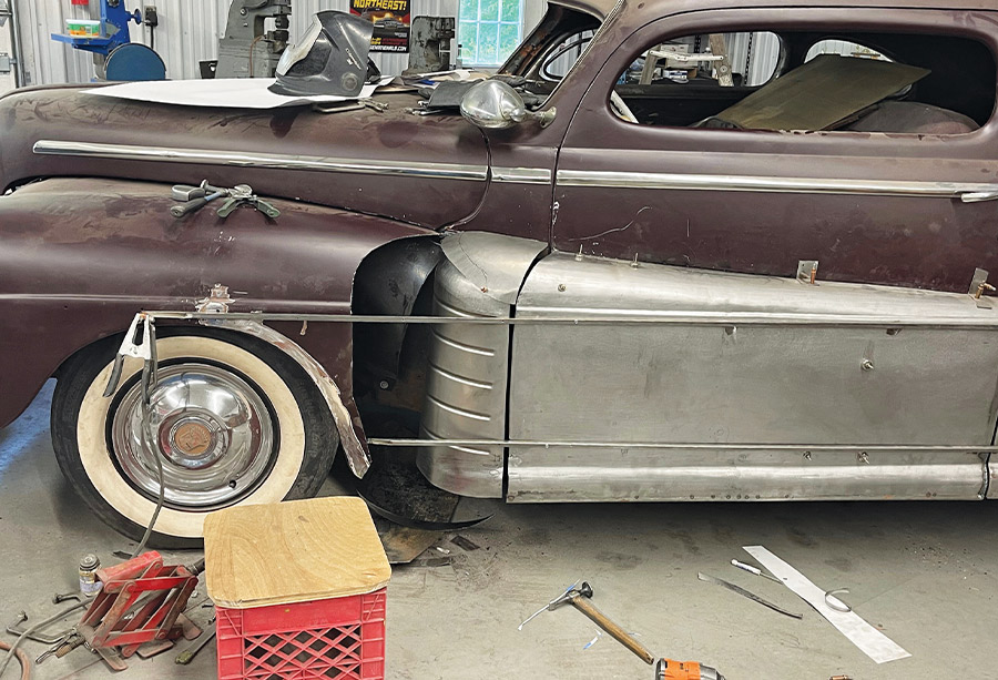 1947 Ford coupe, ribbed fadeaway fender panel fitted, jack stand, tools, and crate in view