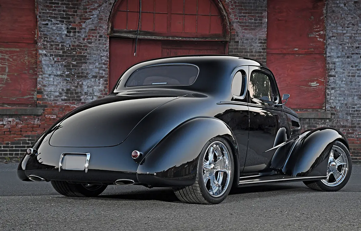 Rear view of a fully customized vintage car with high-gloss black paint and smooth, streamlined body lines