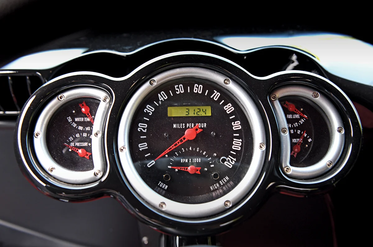 Close-up of a custom car's dashboard gauge cluster, showing the 120 MPH speedometer, tachometer, water temperature, oil pressure, fuel level, and volt gauges.
