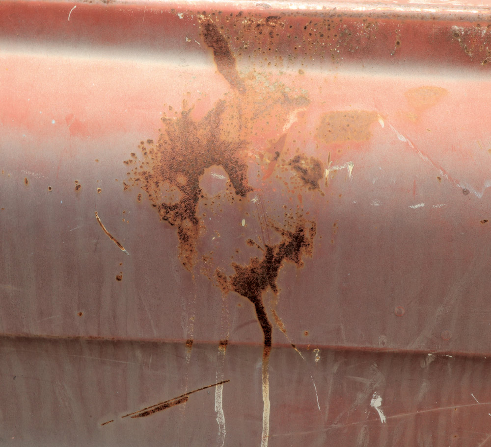 A close-up of the truck's body panel, showing a distinct pattern of severe rust staining and corrosion with drips of white material running down the surface.