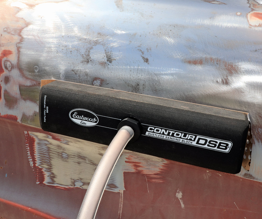 The Eastwood Contour DSB Dustless Sanding Block attached to a hose, being used to sand the side of the truck where paint and bare metal are exposed.