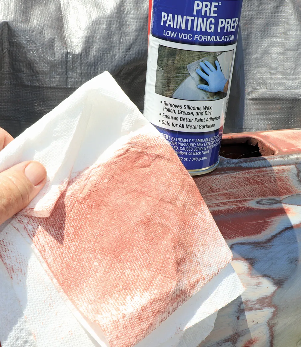A dirty paper towel, stained reddish-brown from cleaning residue, held above a can of "Pre Painting Prep" and the sanded truck panel.
