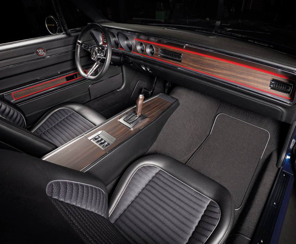 Wide view of the custom interior, featuring black leather seats with ribbed cloth inserts, a wood-grain center console, and a dash with a red accent line.