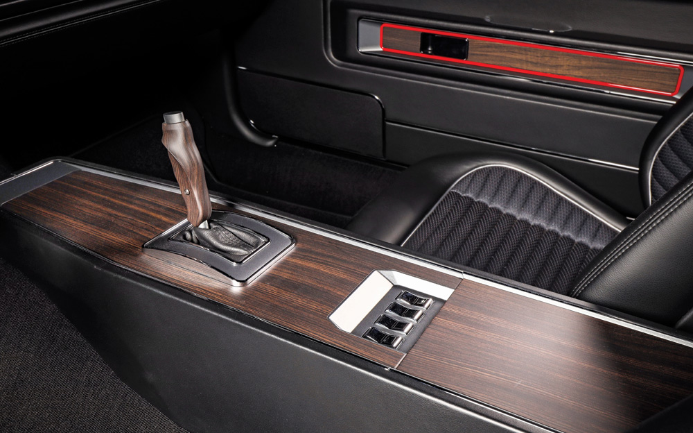 Close-up of the custom interior's center console with dark wood grain trim. It highlights the automatic shifter and a panel of toggle-style switches near the armrest.
