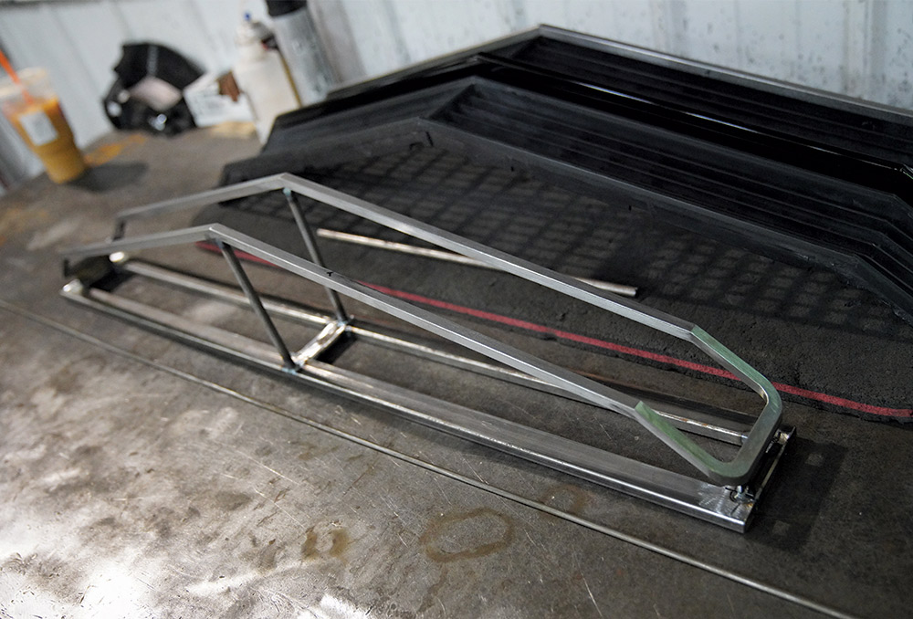 A custom-fabricated steel grille frame component in a shop holding the trim pieces in alignment