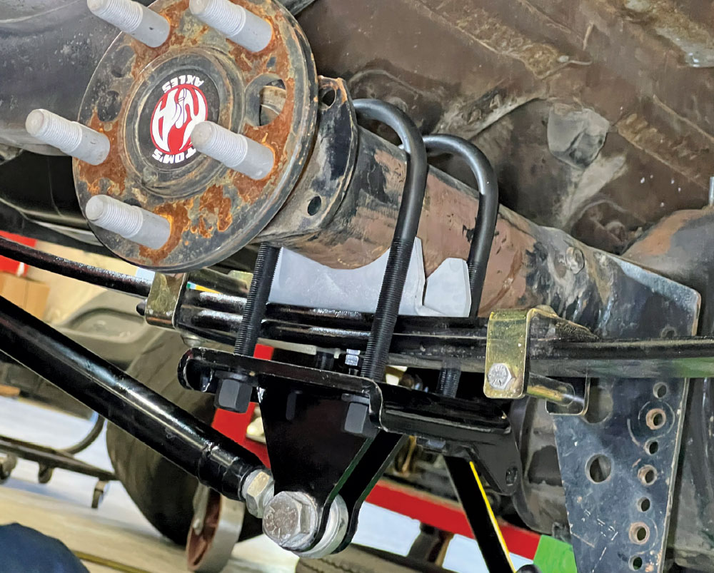 Close-up view of a vehicle's rear axle assembly with U-bolts and control arms