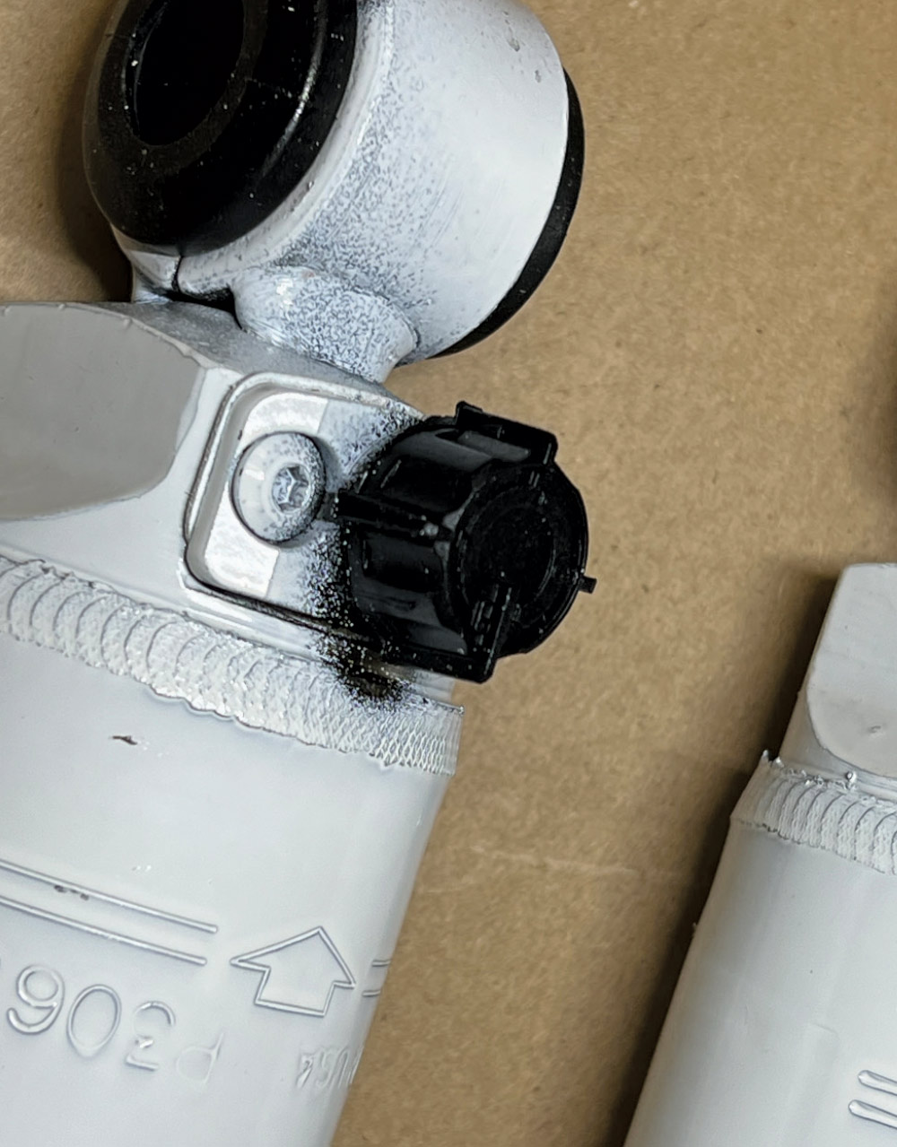 Close-up of a white adjustable shock absorber showing the black plastic 9-way adjustment knob on the body and mounting eyelet.