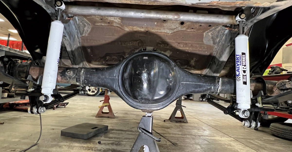 Under-vehicle shot showing installed white Calvert Racing CR Series adjustable shocks and suspension bars.