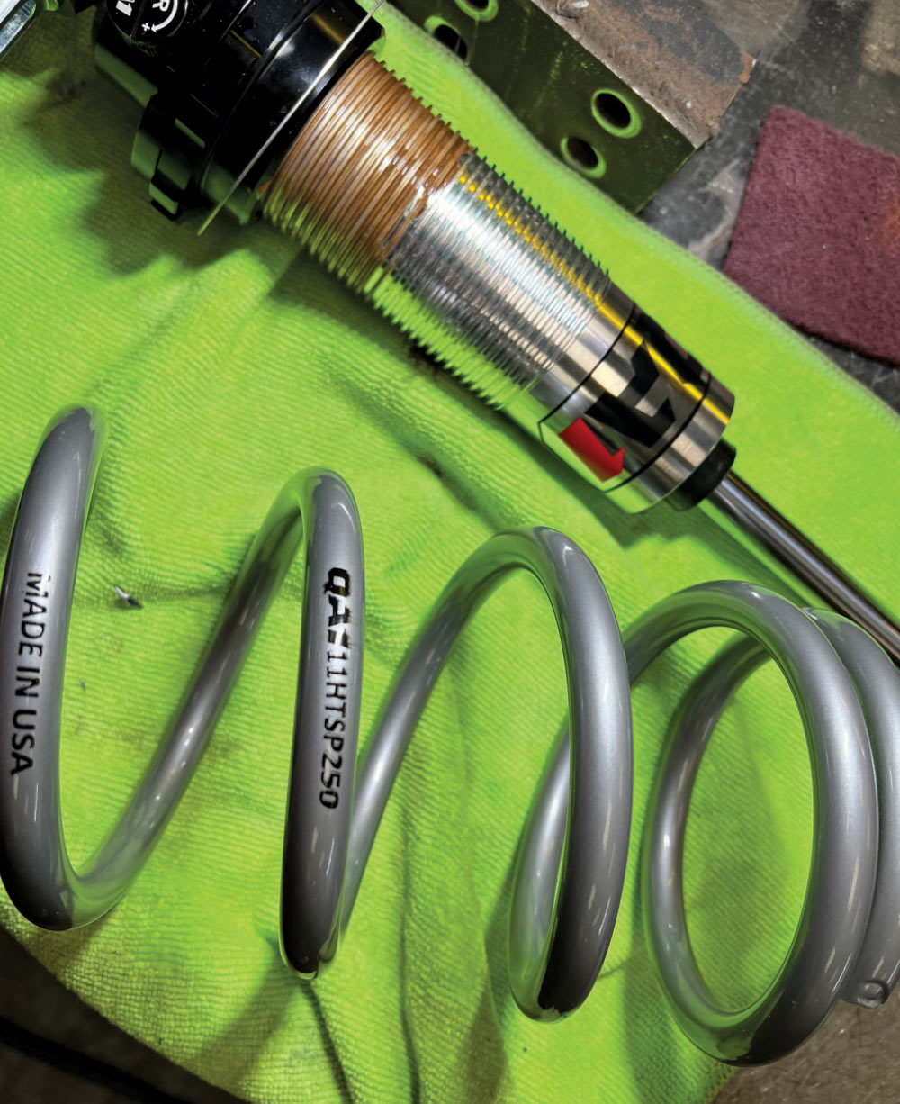 A threaded coilover shock body resting on a bright green cloth.