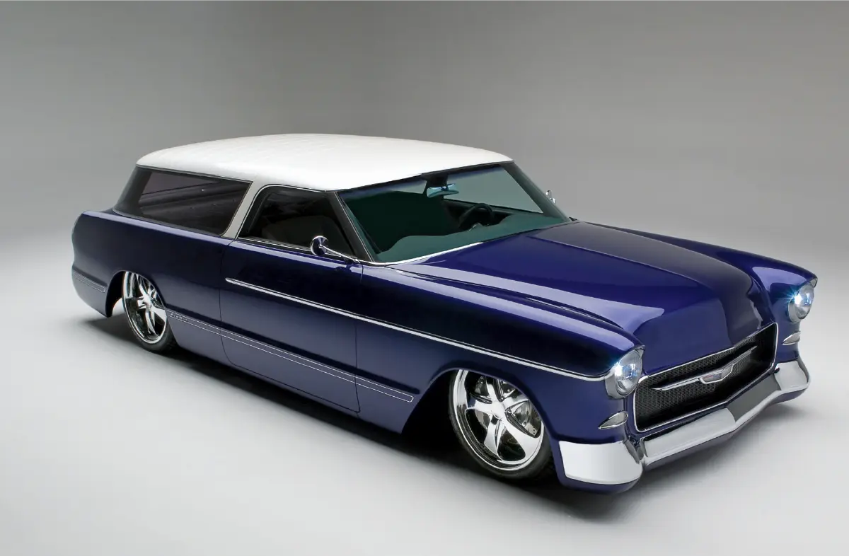 A customized blue and white vintage 1955 Chevrolet Nomad station wagon; The vehicle has a white roof, a deep metallic blue body, custom chrome wheels, and a lowered suspension