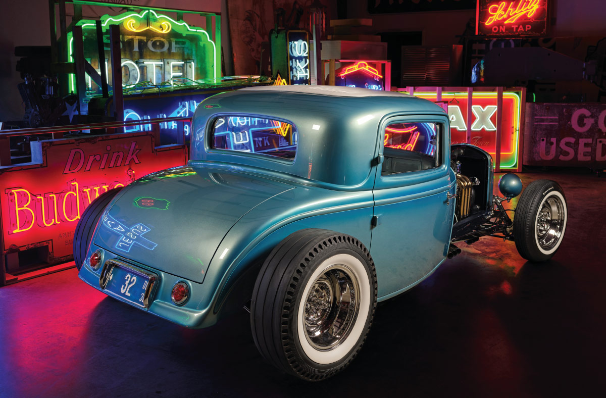 1932 Ford five-window teal coupe detailed neon-lit shot with polished suspension and wide whitewalls