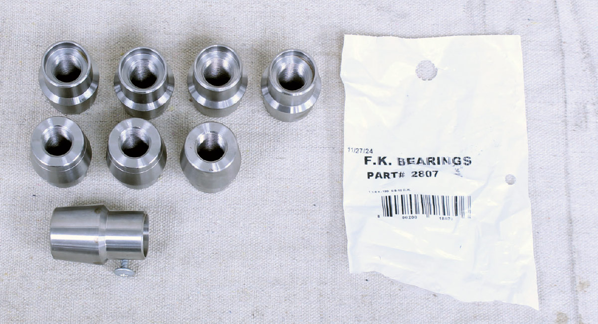 Eight machined steel rod end bungs and a white plastic parts bag from F.K. Bearings.