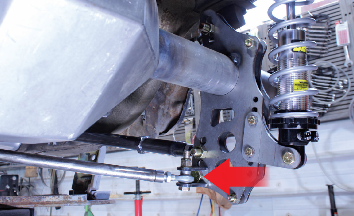 Underside view of a vehicle showing a coilover shock and suspension links connected to a custom axle mounting plate.