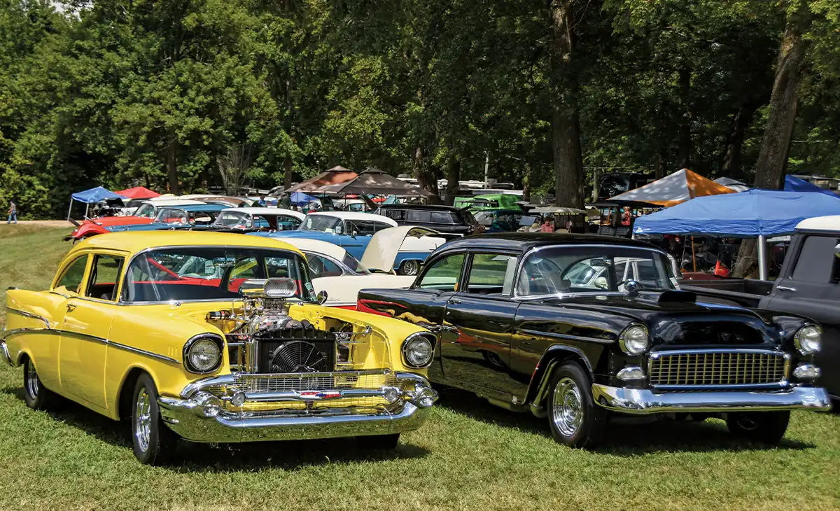 Yellow 1957 Chevrolet with blown engine, black 1955 Chevy beside, chrome wheels