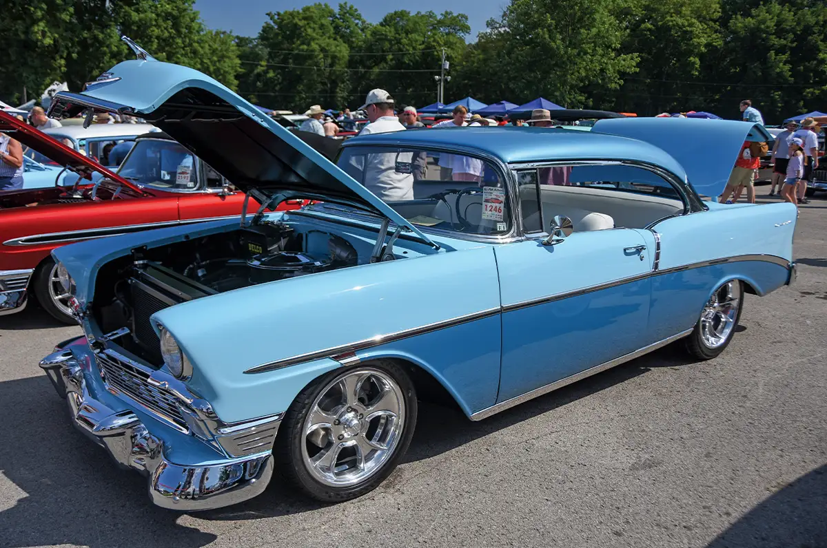 Light blue 1956 Chevrolet Bel Air, hood raised, chrome wheels, event sticker 1246