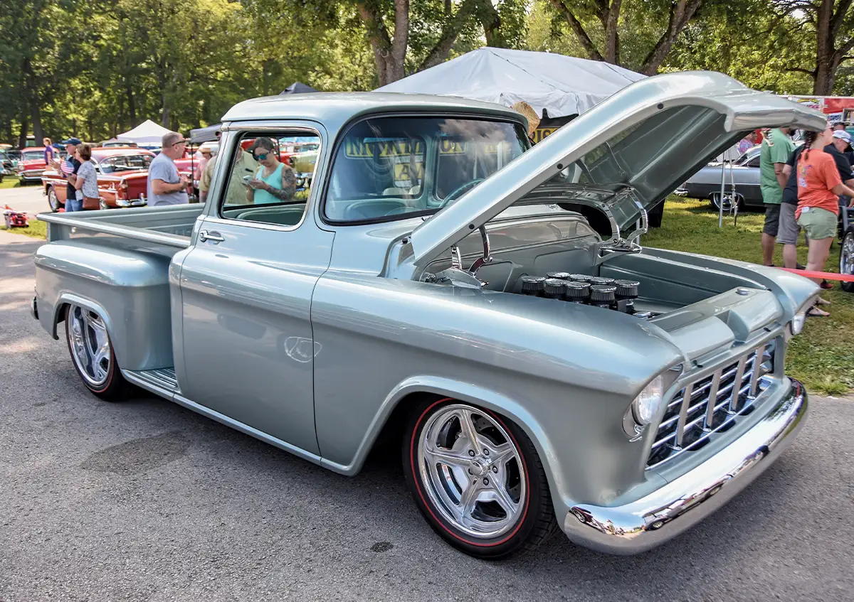 Custom silver-gray Chevrolet pickup, hood open, performance engine with intake stacks