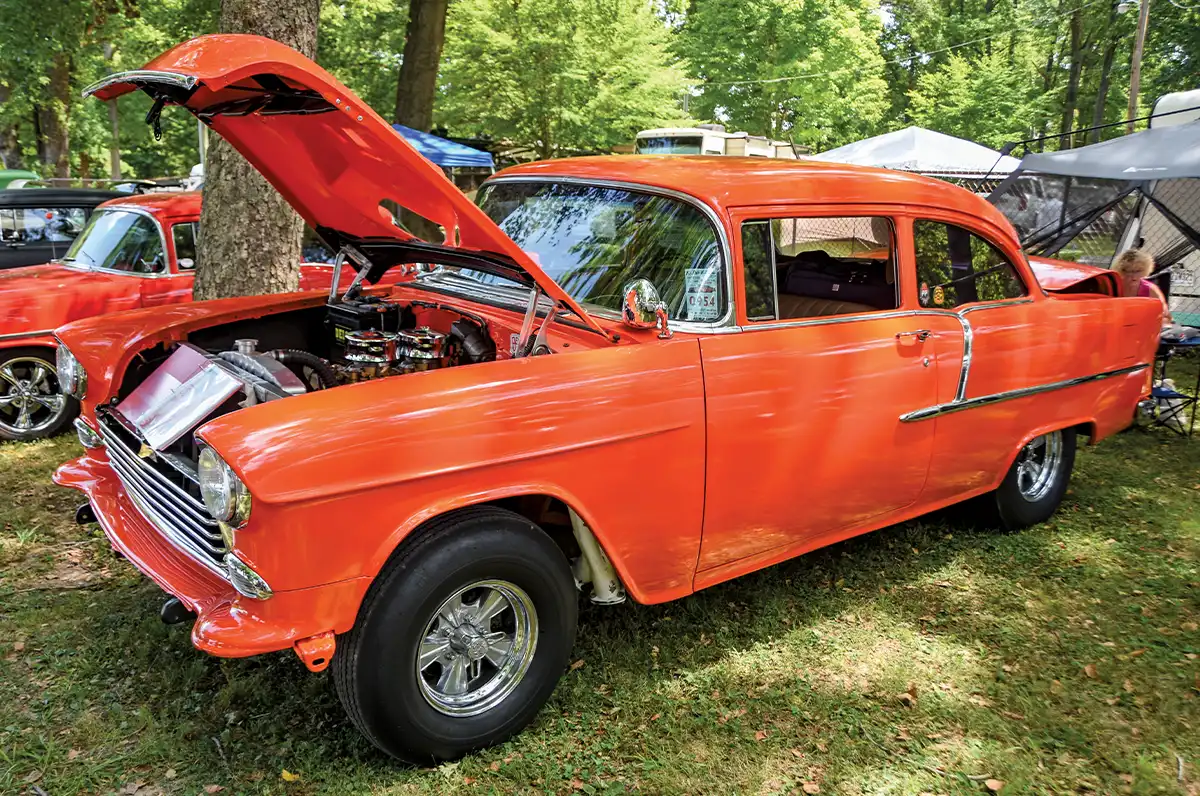 Orange 1955 Chevrolet gasser, hood open, chrome wheels, event sticker 054