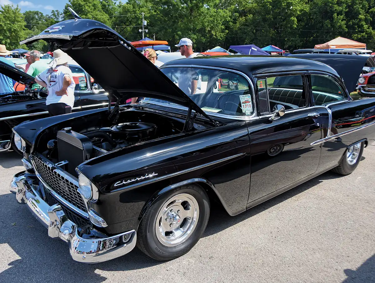 Black Chevrolet with hood open, chrome wheels, event sticker 1713, car show setting