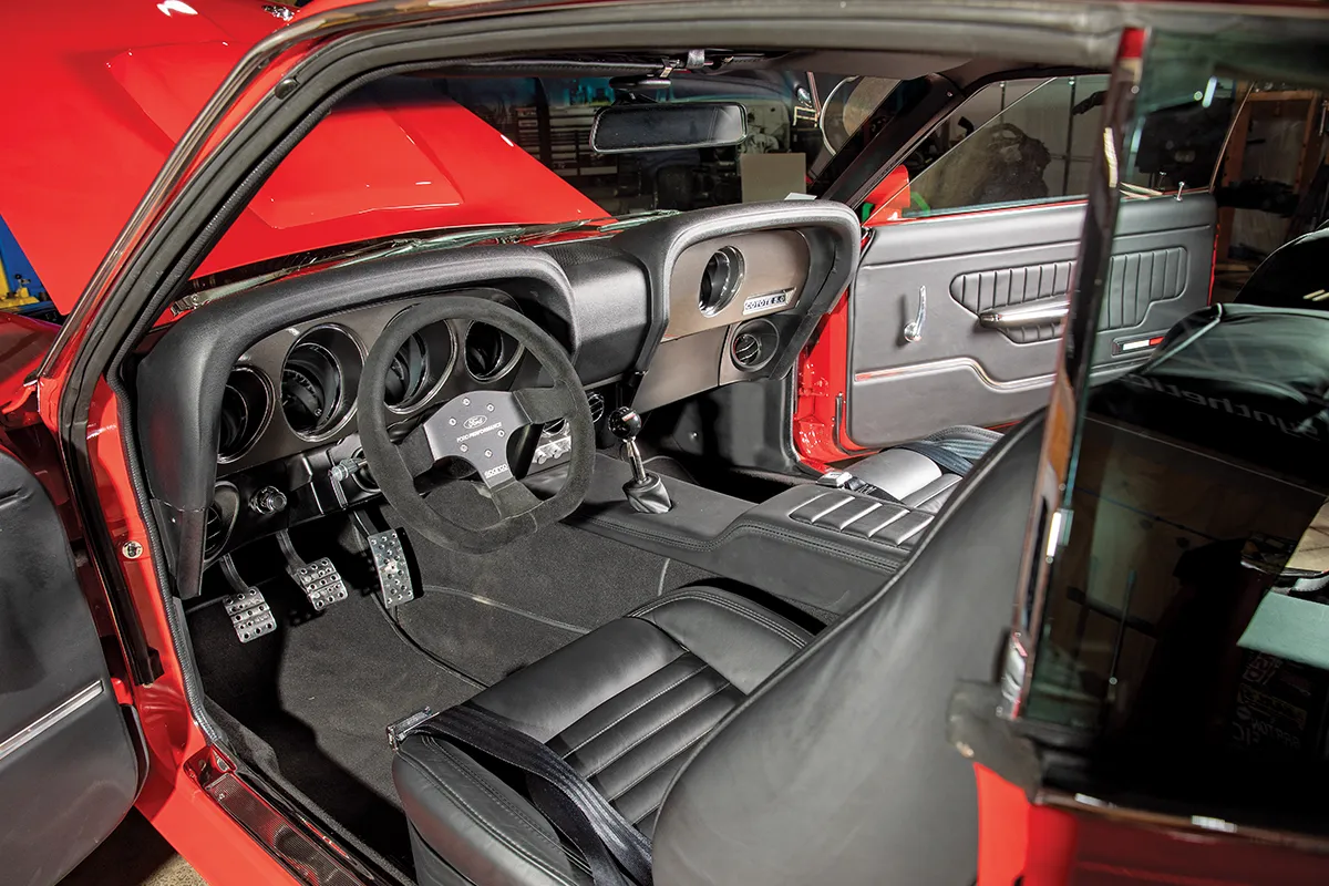 Custom black leather interior of a classic red Ford Mustang featuring Sparco racing steering wheel and modern performance upgrades.