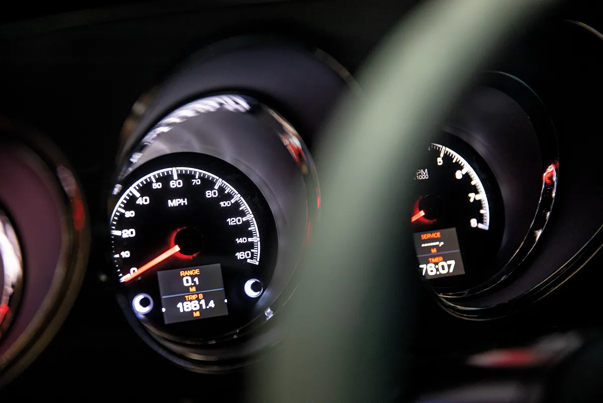 Close-up of modern illuminated analog gauges in a classic Ford Mustang dashboard, showing a 160 MPH speedometer and a digital trip display.