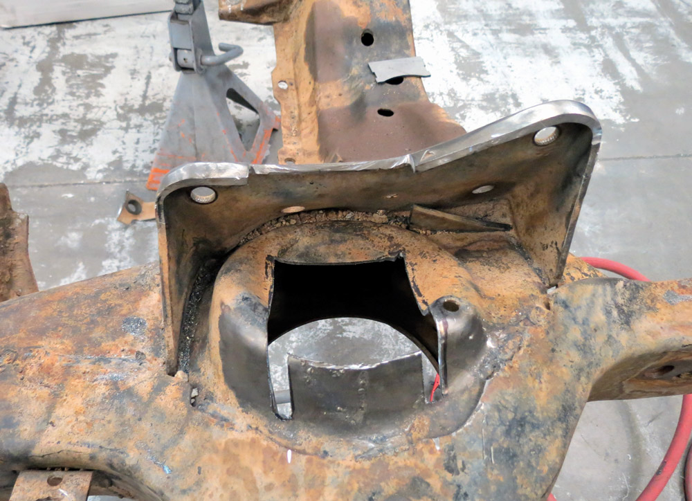 A close-up of the rusted chassis after a section has been cut away, showing the raw metal edges and the interior cavity of the frame rail prepared for reinforcement.