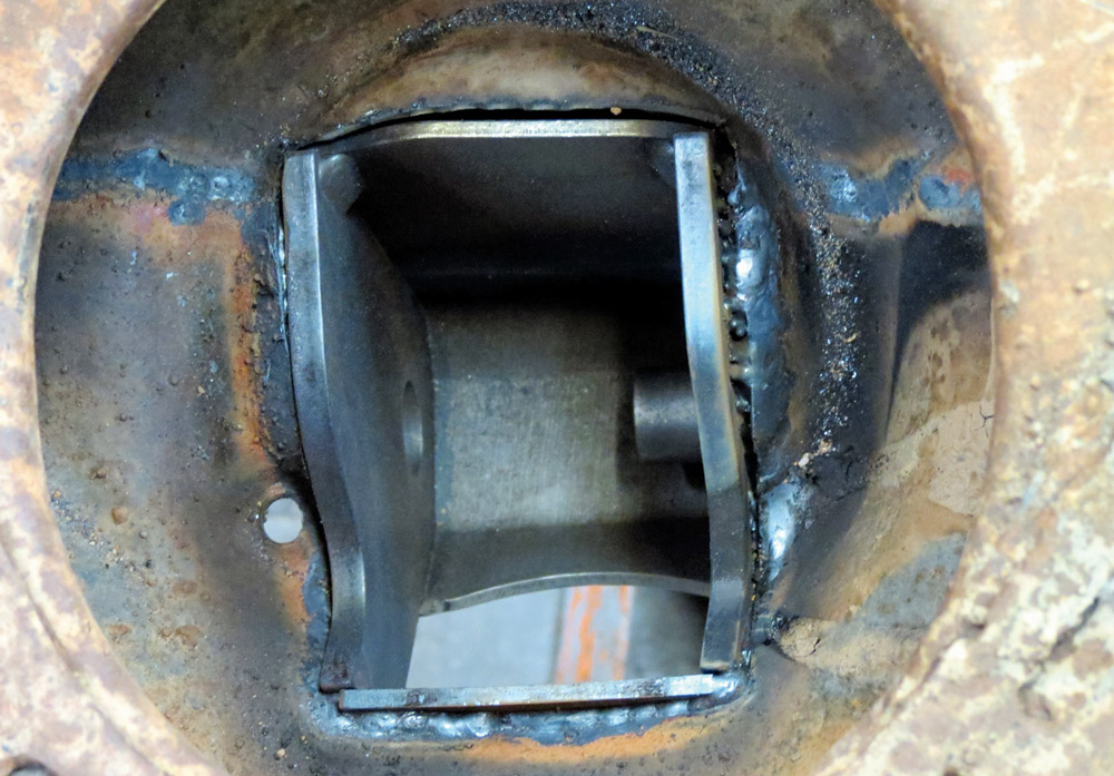 Close-up view of a freshly completed weld inside a frame pocket, showing the beads of metal joining a new steel sleeve to the interior of the Corvette's chassis rail.