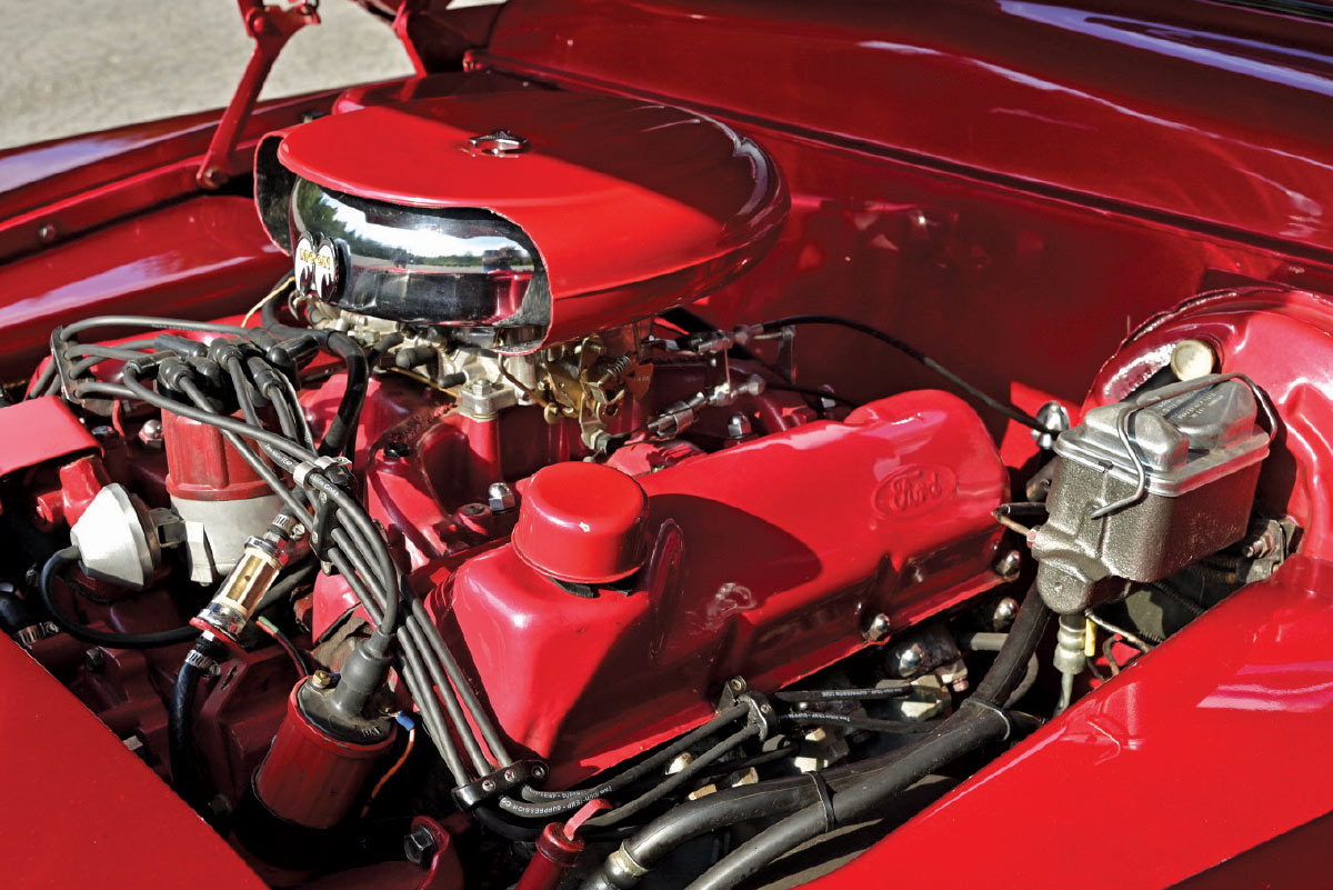 Close-up of the clean engine bay featuring a Ford V8 engine painted to match the car's candy red exterior.