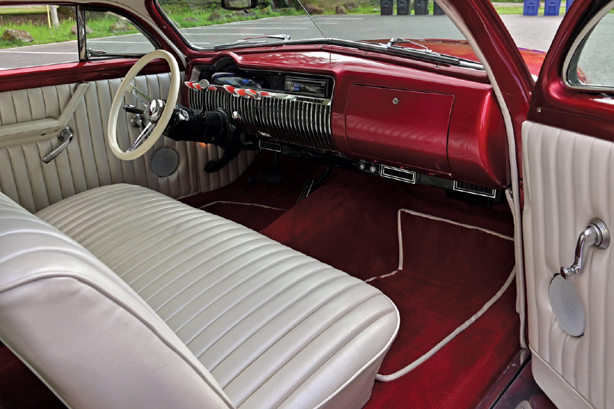 Interior view of the front seat and dashboard, showcasing a white steering wheel and matching off-white pleated upholstery.
