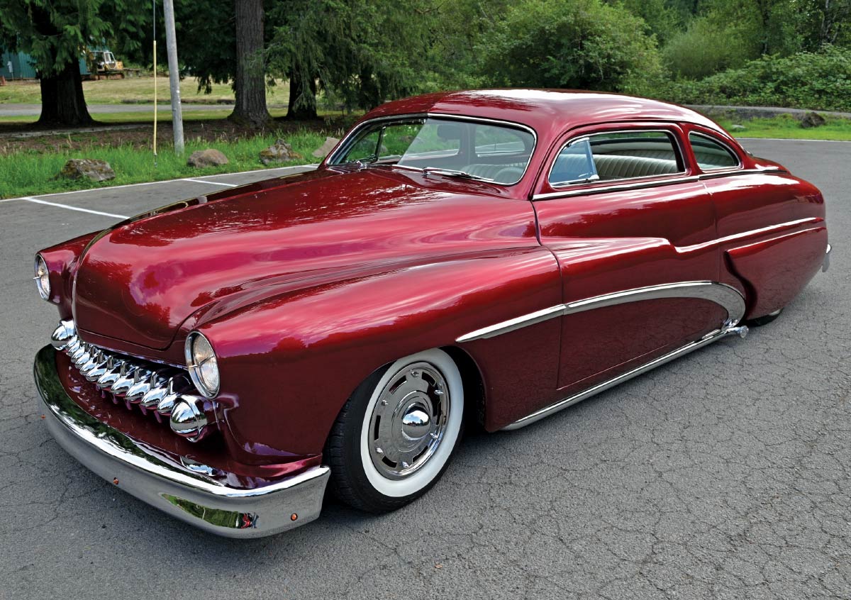 High-angle front perspective of the red custom Mercury parked in a lot, showing its low stance and polished chrome bumpers.