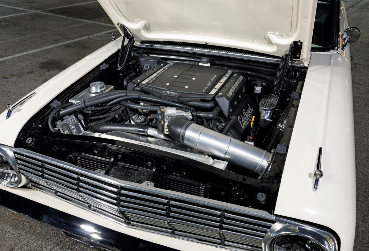 Open hood view of a high-performance engine bay featuring an Edelbrock supercharger and custom silver intake piping.