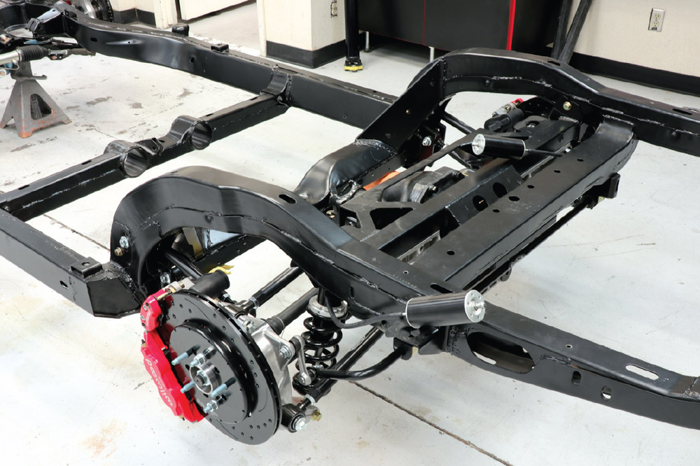 Completed Detroit Speed IRS and red Wilwood brakes installed on a black C3 Corvette chassis. Features include the rear differential, coilovers, and remote shock reservoirs mounted to the frame rails.