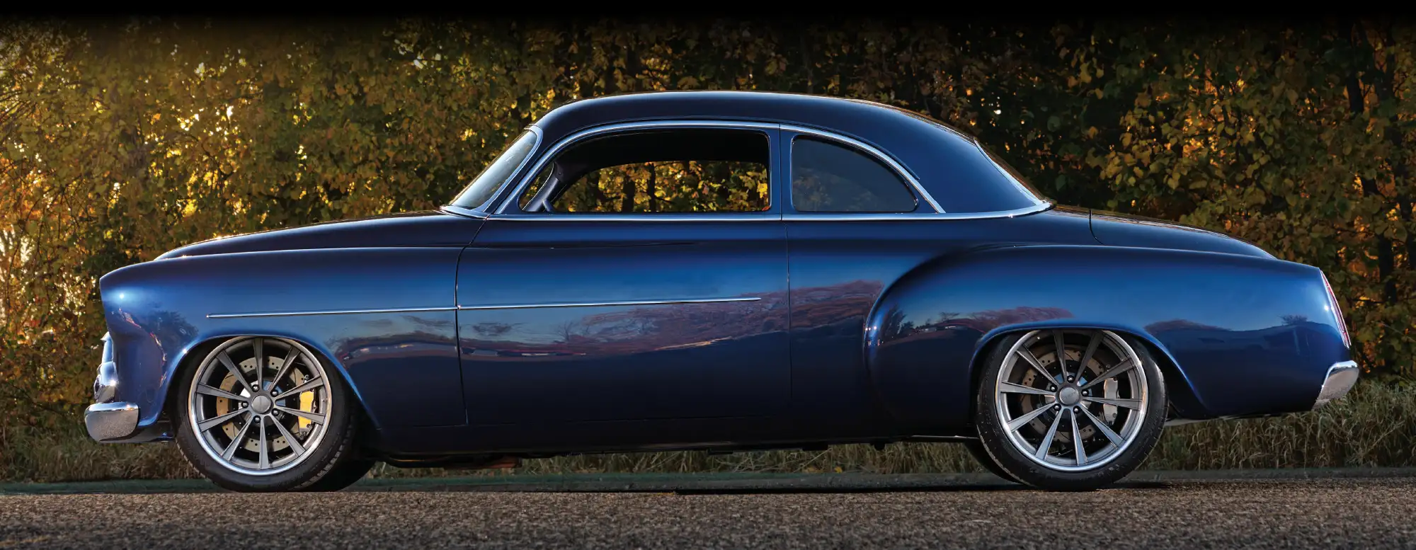 1952 chevy styleline side view deep blue paint lowered stance custom wheels autumn backdrop