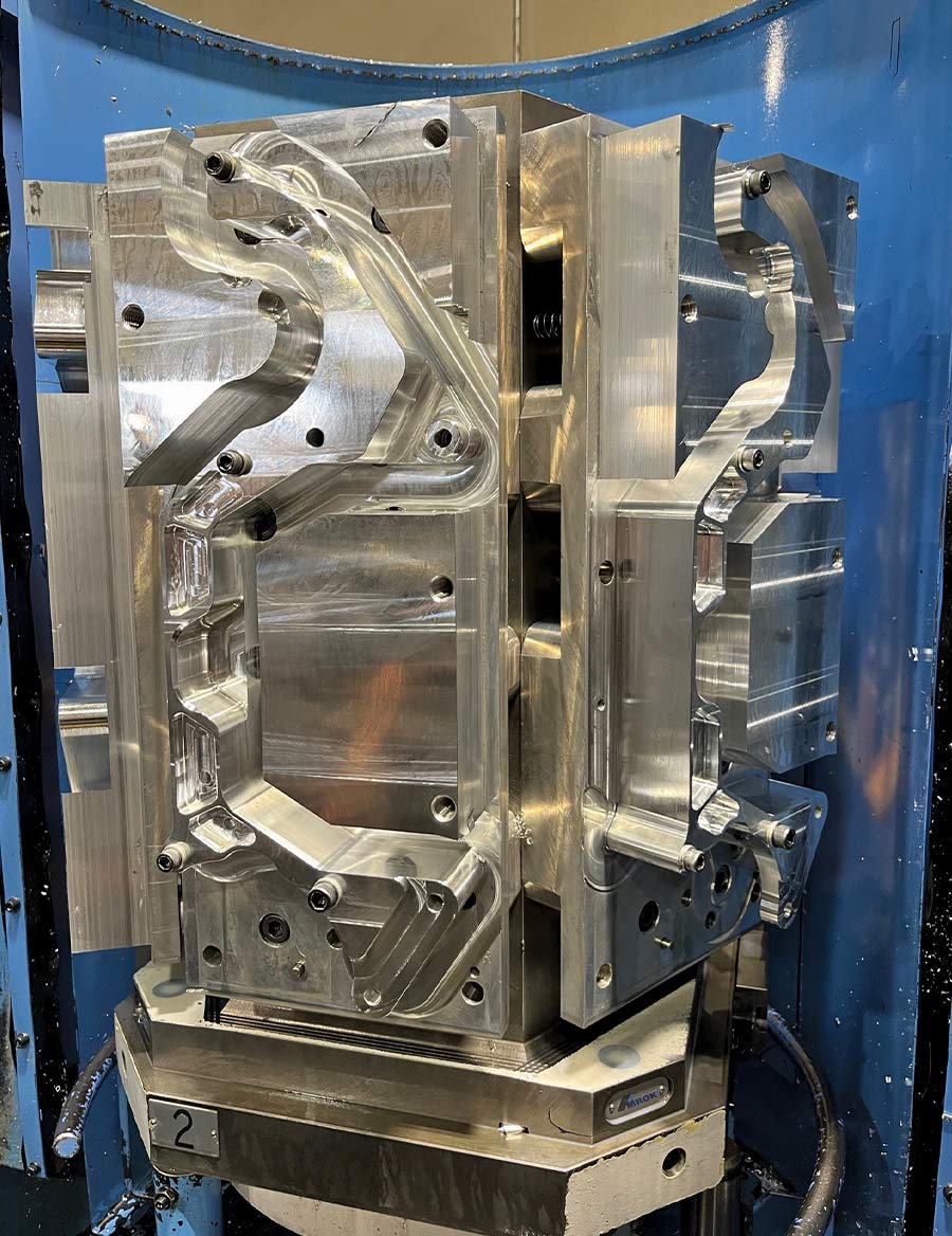A large, multi-sided CNC machining fixture holding several polished aluminum Front Runner engine brackets during the precision milling process in an industrial machine shop