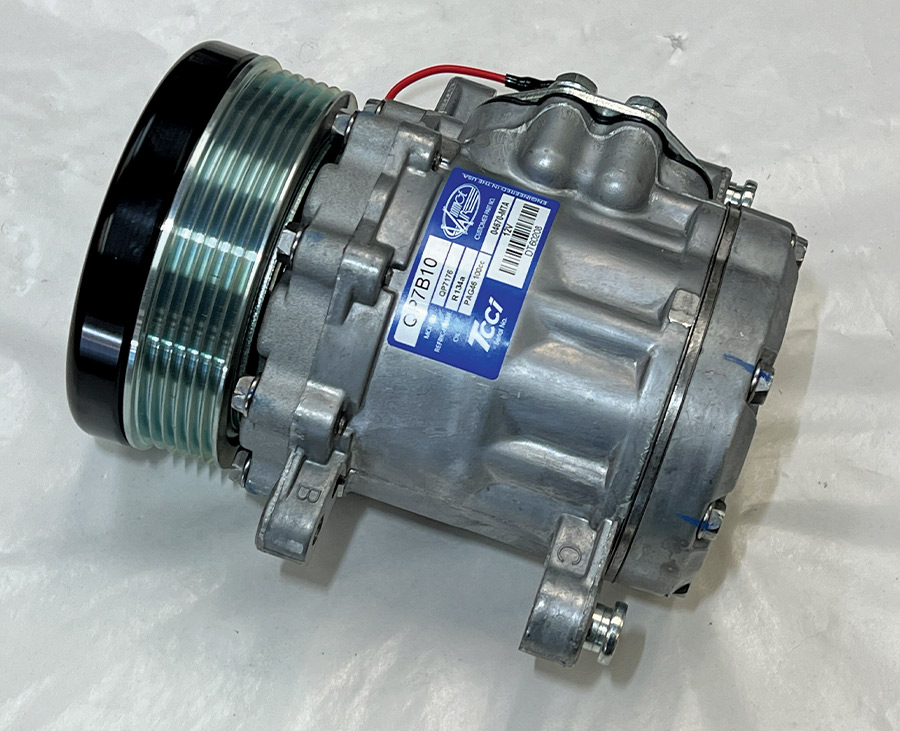 A high-performance TCCI air conditioning compressor for a Front Runner engine drive system, featuring a compact aluminum body and a black serpentine pulley, shown on a white surface