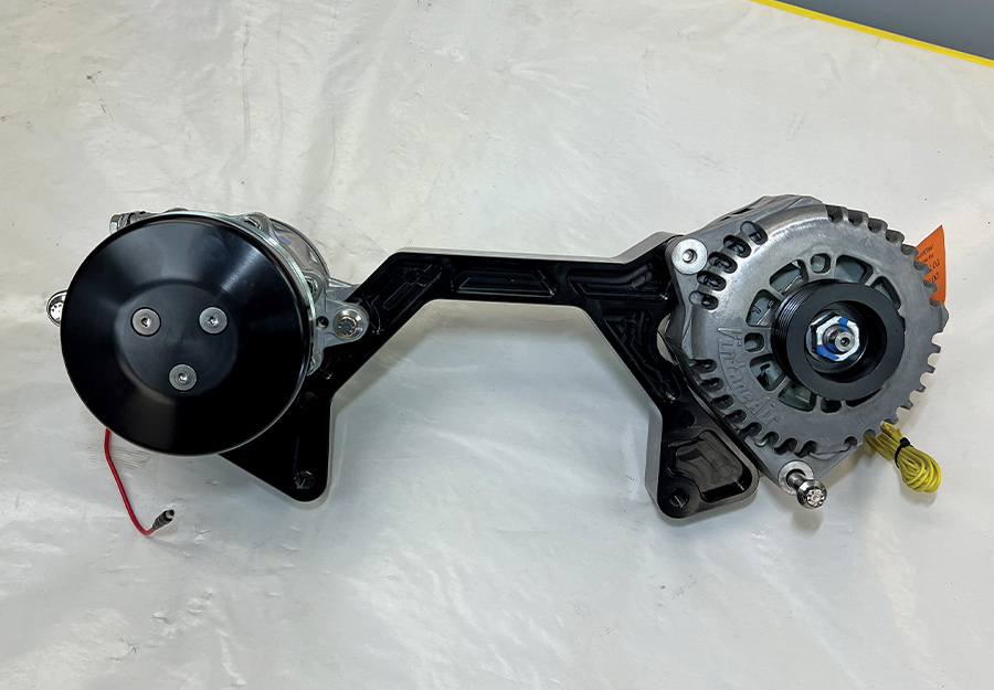 A top-down view of a partially assembled Front Runner engine accessory drive, featuring a black anodized mounting bracket connecting a high-performance A/C compressor and a high-output alternator